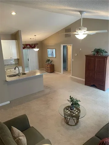 a living room with furniture a chandelier and a view of kitchen