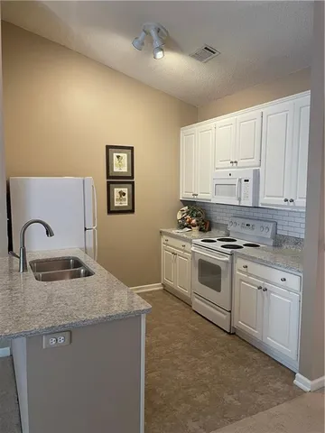 a kitchen with granite countertop a stove sink and cabinets