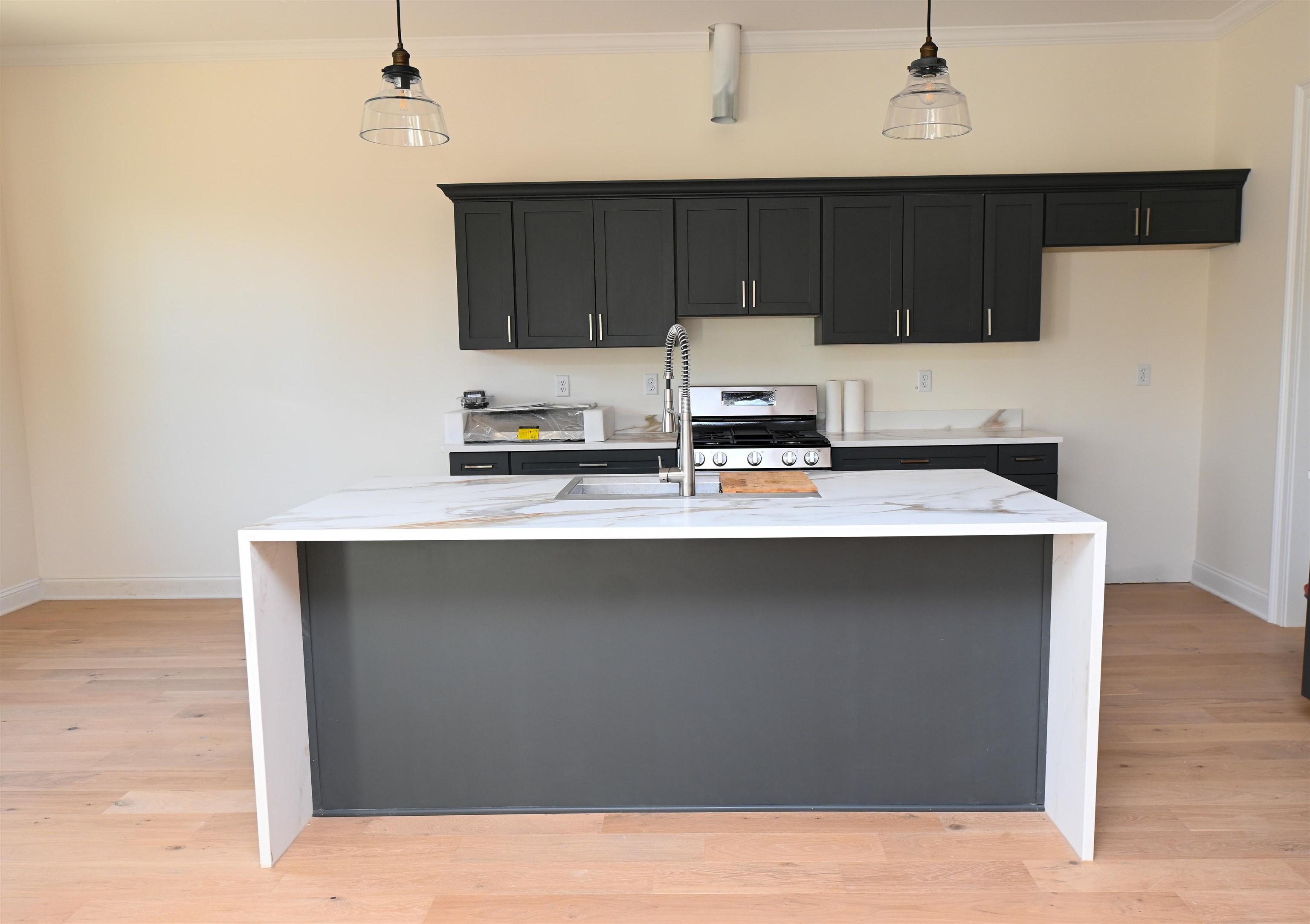 2939 Brighton-Clopton Road Brighton, TN 38011 - Photo 10 of 23 Kitchen featuring light stone countertops, stainless steel range with gas stovetop, an island with sink, dark cabinetry, and ornamental molding
