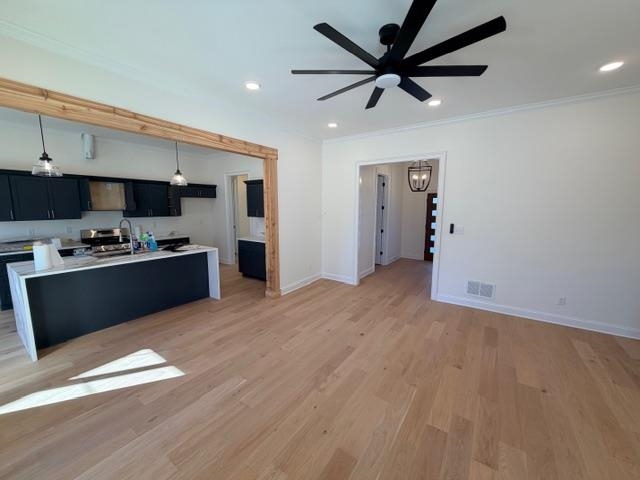 2939 Brighton-Clopton Road Brighton, TN 38011 - Photo 7 of 23 Kitchen featuring dark cabinets, hanging light fixtures, a kitchen island with sink, light wood-style floors, and ornamental molding