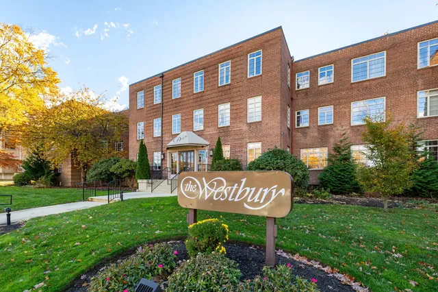 a view of a brick building with a yard and bench