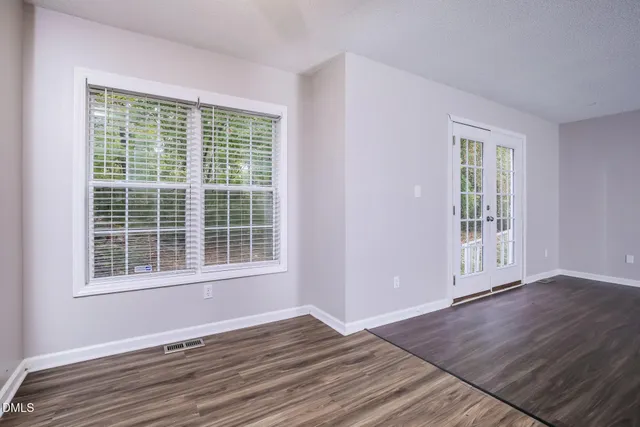 a view of an empty room with wooden floor and a window