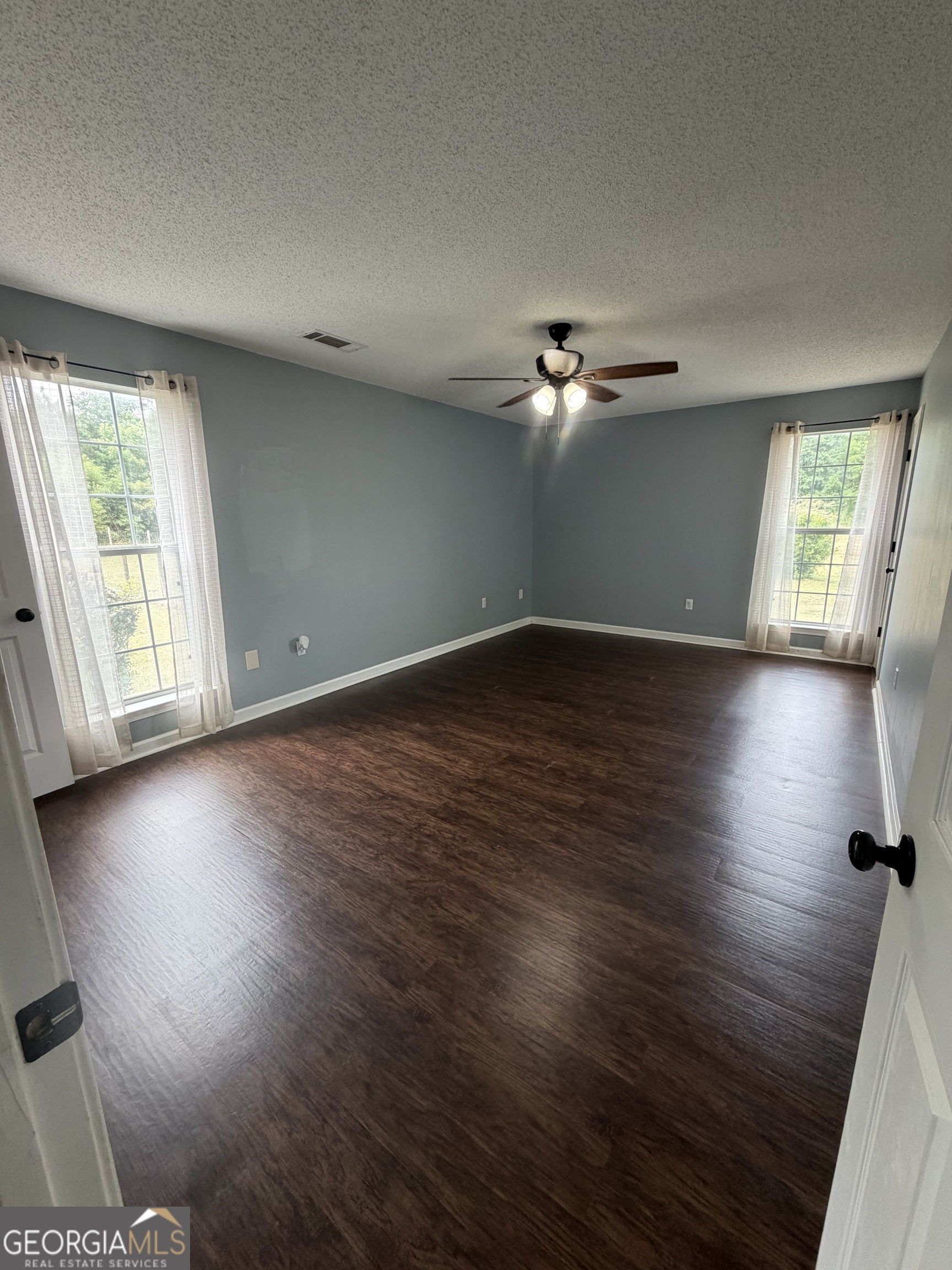 1410 Greensboro Road Madison, GA 30650 - Photo 8 of 17 an empty room with wooden floor chandelier fan and windows