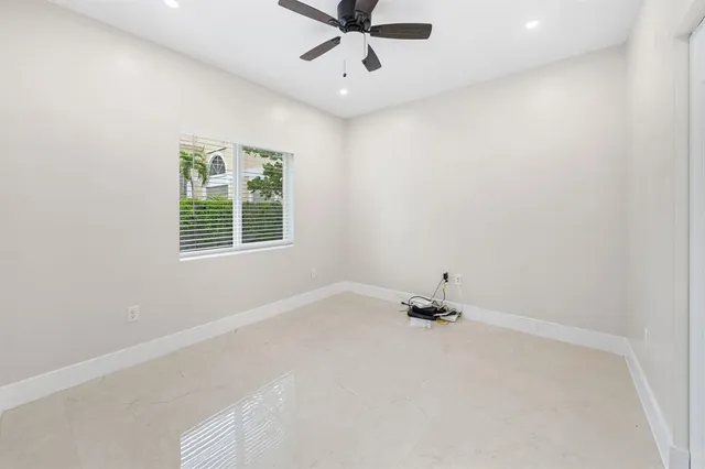 an empty room with a window and a ceiling fan