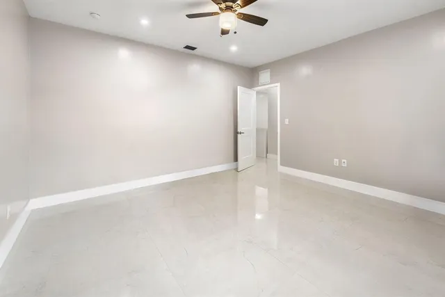 an empty room with ceiling fan and window