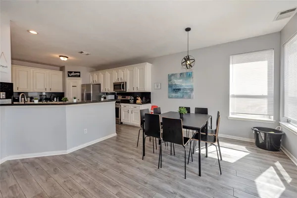 a kitchen with stainless steel appliances granite countertop a stove top oven a sink a refrigerator with a dining table and chairs