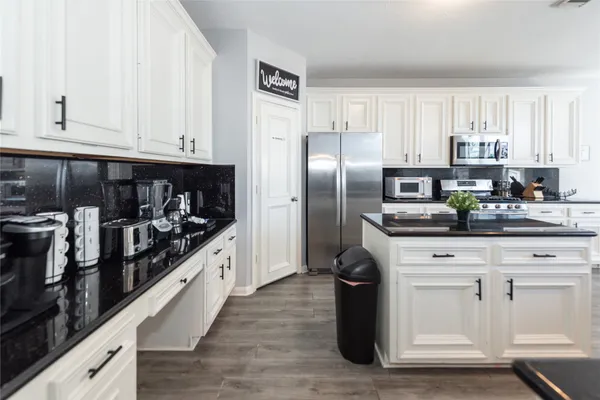 a kitchen with stainless steel appliances kitchen island granite countertop a stove a sink and white cabinets