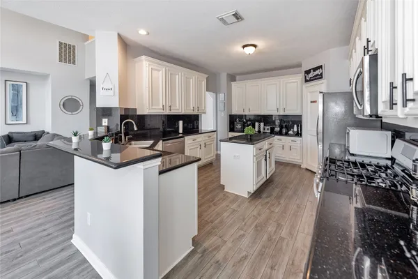 a kitchen with granite countertop a refrigerator stove top oven and sink