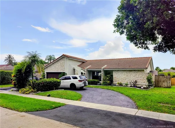 a front view of a house with a garden and trees