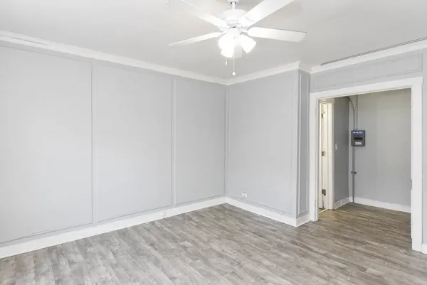 an empty room with wooden floor and fan