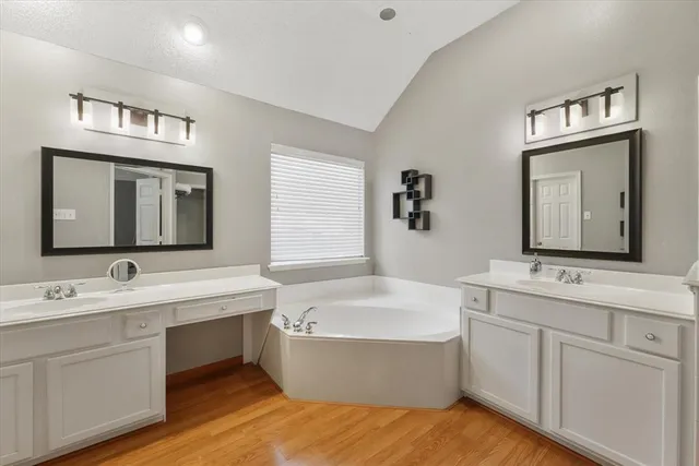 a bathroom with a tub double sink window and mirror