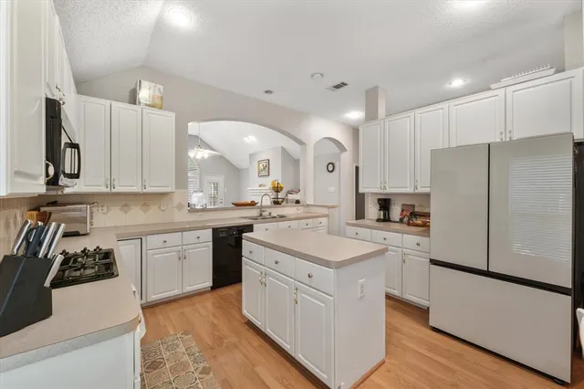 a kitchen with white cabinets and refrigerator
