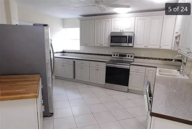a kitchen with granite countertop white cabinets and stainless steel appliances