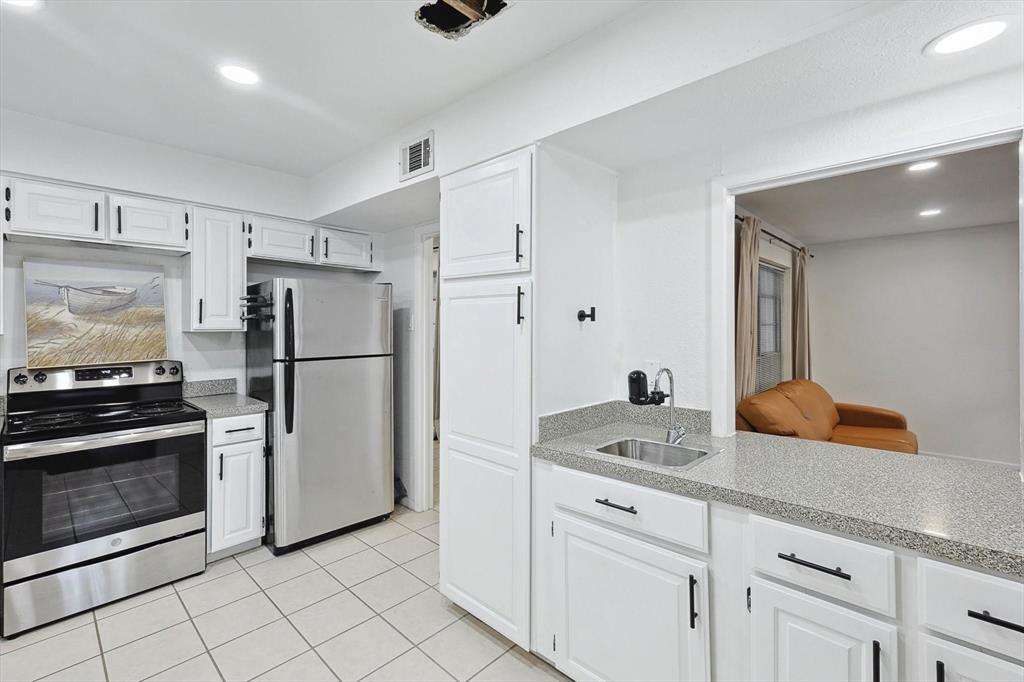 9801 Smokefeather Lane Dallas, TX 75243 - Photo 15 of 27 a kitchen with white cabinets and stainless steel appliances