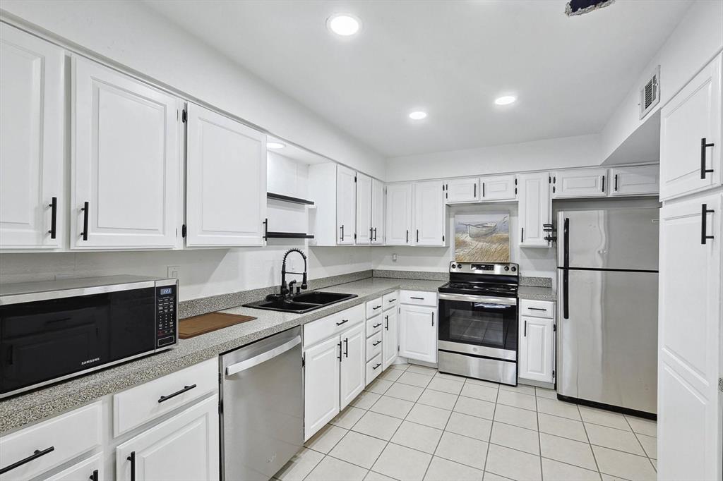 9801 Smokefeather Lane Dallas, TX 75243 - Photo 16 of 27 a kitchen with white cabinets and stainless steel appliances