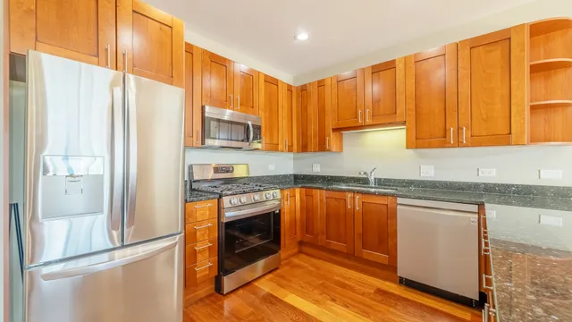 a kitchen with stainless steel appliances granite countertop a stove a sink and a refrigerator