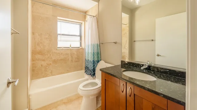 a bathroom with a granite countertop sink toilet and shower