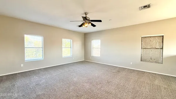 an empty room with windows and ceiling fan