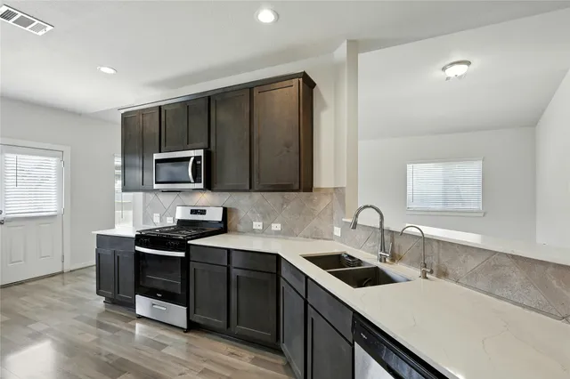 a kitchen with a sink and a stove top oven with wooden floor