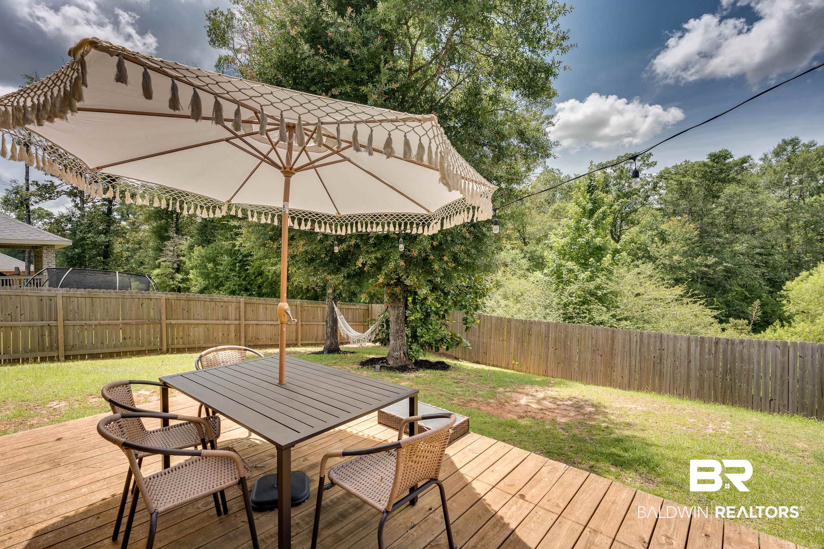 2215 Fernwood Loop West Semmes, AL 36575 - Photo 31 of 40 Expansive backyard featuring a wood deck, wood privacy fencing, string lighting, and mature trees