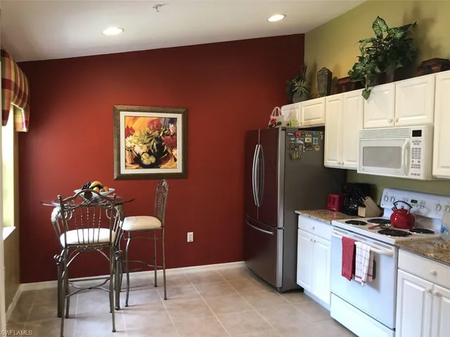 a kitchen with stainless steel appliances kitchen island granite countertop a refrigerator and a dining table