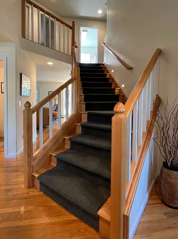 a view of staircase with lots of frames on wall and wooden floor