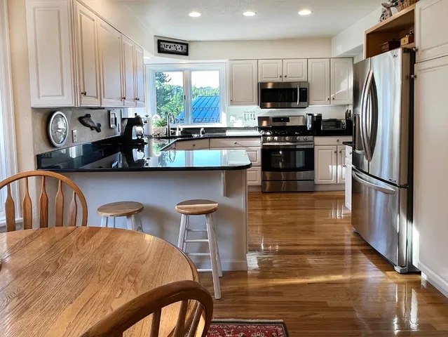 a kitchen with stainless steel appliances a stove a sink a microwave a refrigerator and chairs