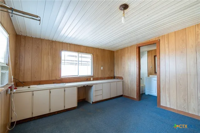 a view of an empty room with window and cabinet