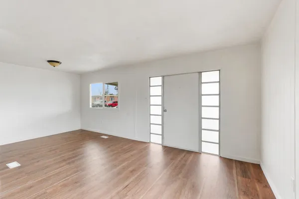 an empty room with wooden floor and windows