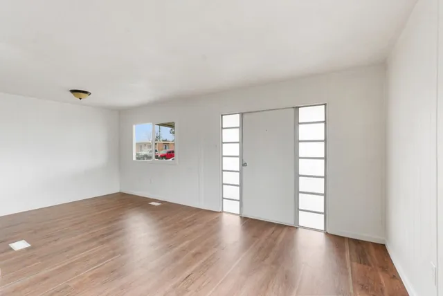 an empty room with wooden floor and windows