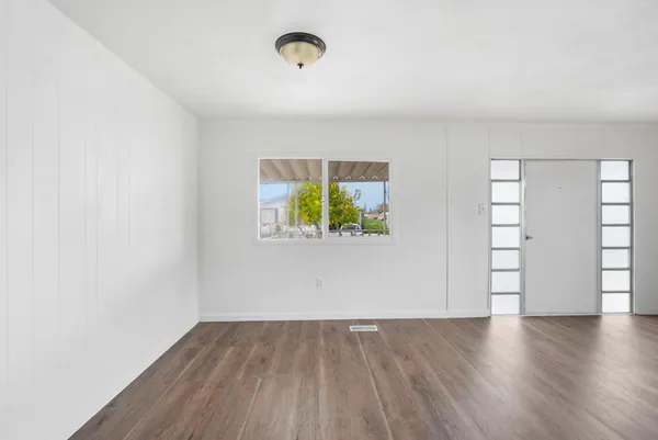 an empty room with wooden floor and windows
