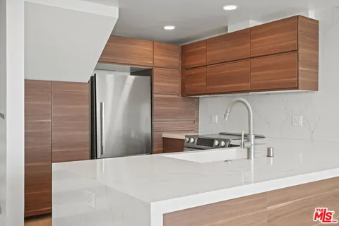 a kitchen with stainless steel appliances kitchen island a refrigerator sink and cabinets