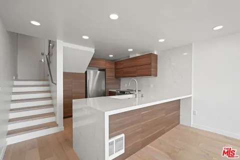a large kitchen with a large counter top a sink and stainless steel appliances