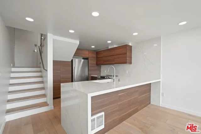 a large kitchen with a large counter top a sink and stainless steel appliances