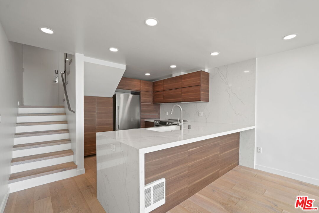 6 Voyage Street, Unit 108 Marina del Rey, CA 90292 - Photo 7 of 27 a large kitchen with a large counter top a sink and stainless steel appliances