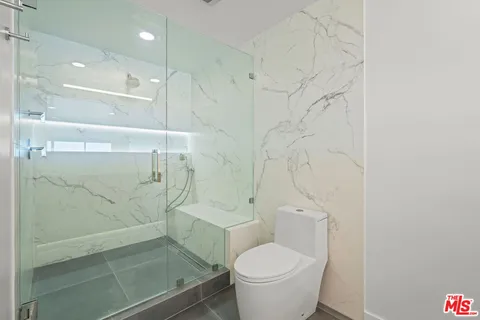 a bathroom with a granite countertop shower and a toilet