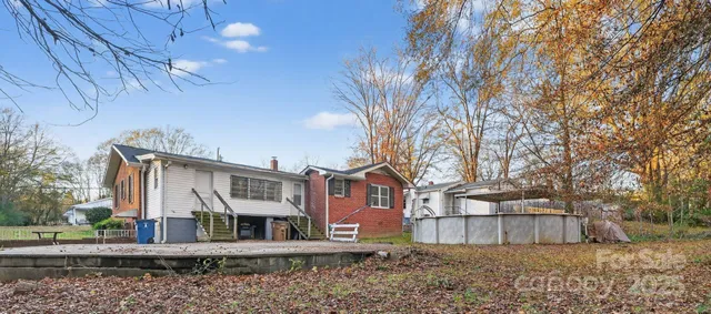a view of a white house with a large tree next to a yard