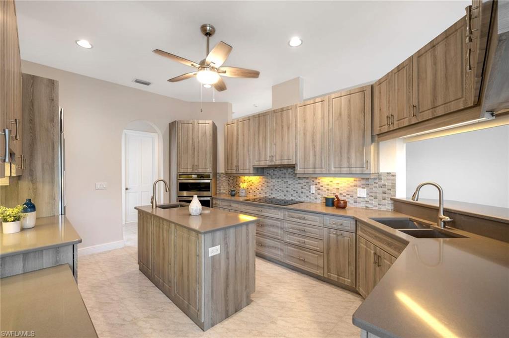 2115 Imperial Golf Course Boulevard Naples, FL 34110 - Photo 11 of 31 a kitchen with stainless steel appliances a sink stove and cabinets