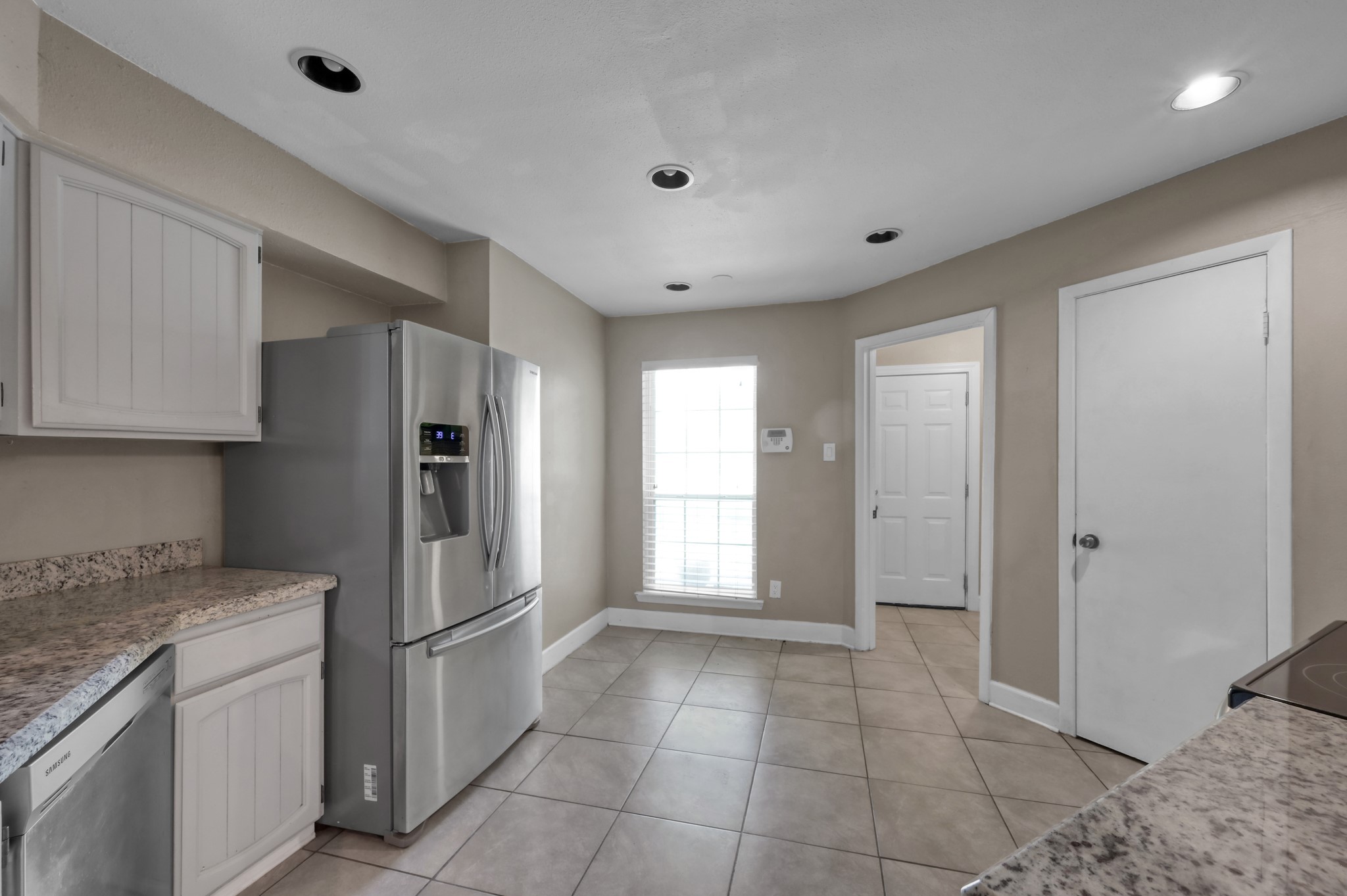 12015 Fallbrook Drive Houston, TX 77065 - Photo 11 of 29 This kitchen features modern stainless steel appliances, including a large refrigerator and dishwasher. It has ample counter space with granite countertops, light cabinetry, tiled flooring, and recessed lighting, creating a bright and functional space.