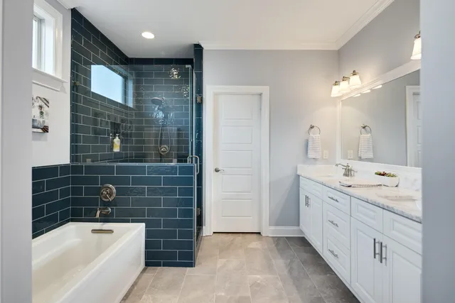 a bathroom with a double vanity sink a large mirror and bathtub