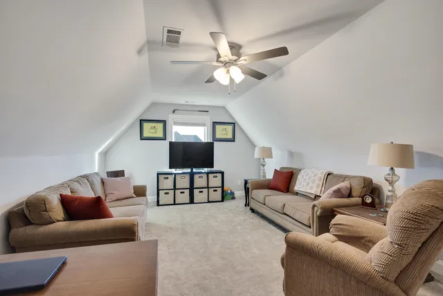 a living room with furniture a ceiling fan a lamp and a window