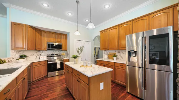 a kitchen with a stove a sink a refrigerator and a dining table with wooden floor