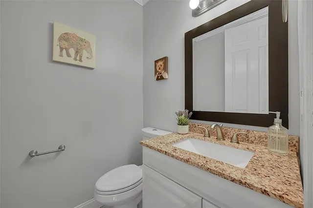 a bathroom with a granite countertop sink a toilet and mirror