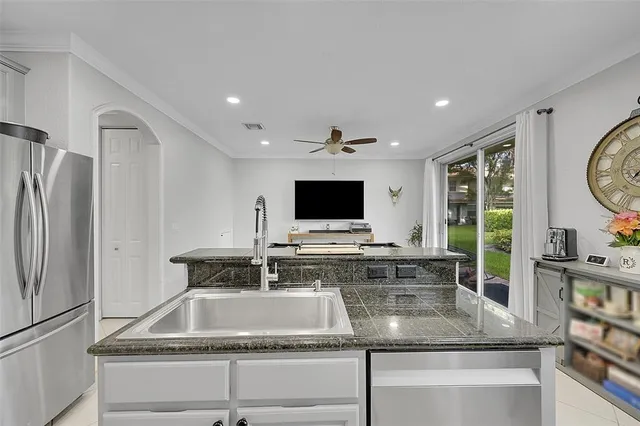a kitchen with kitchen island granite countertop a sink and a refrigerator