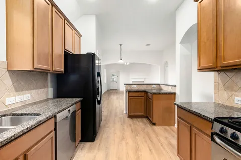 a kitchen with granite countertop a refrigerator and a sink
