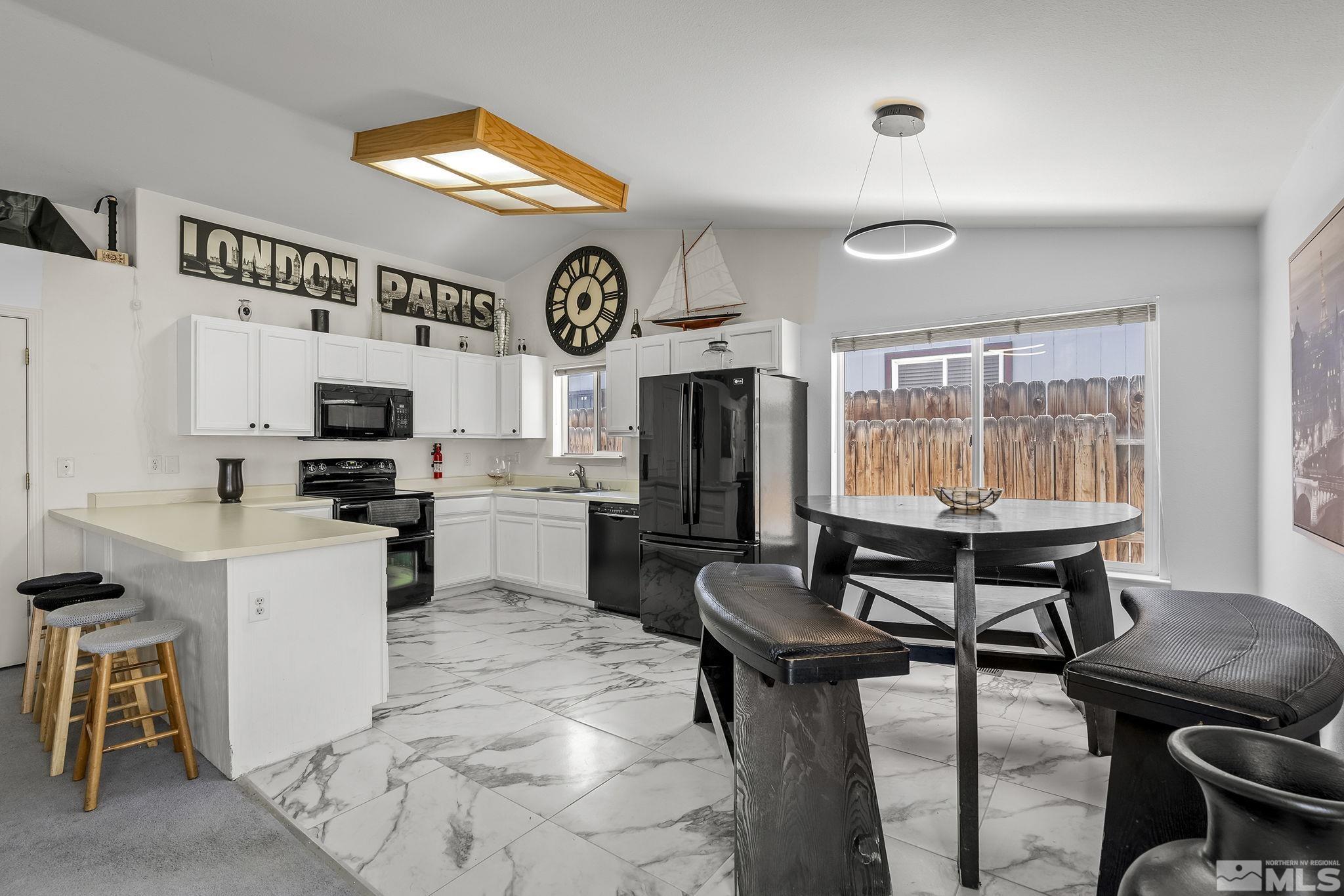 940 Atrium Road Fernley, NV 89408 - Photo 6 of 20 a kitchen with stainless steel appliances granite countertop a stove top oven a sink a dining table and chairs with white cabinets
