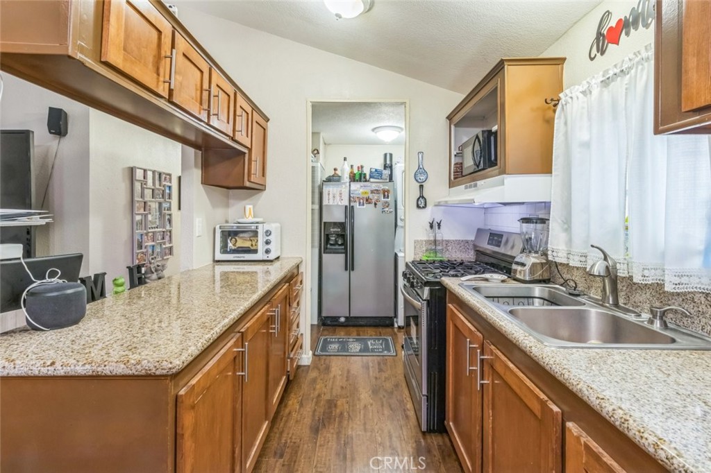8221 Ilex Street, Unit 10 Rancho Cucamonga, CA 92335 - Photo 16 of 27 a kitchen with stainless steel appliances granite countertop a sink a stove and a wooden cabinets
