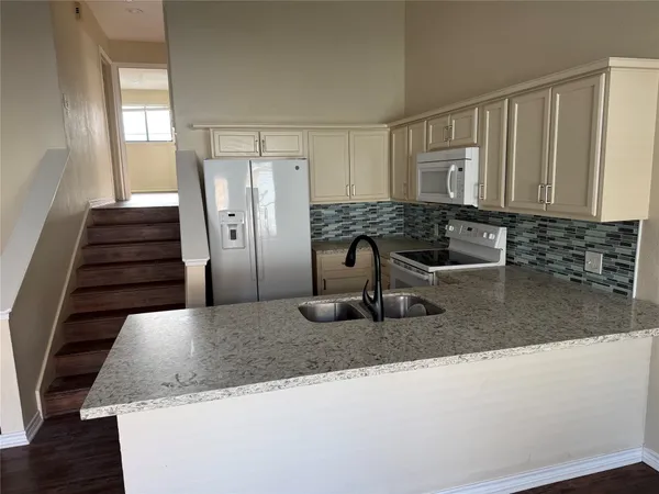 a kitchen with granite countertop a sink and a refrigerator