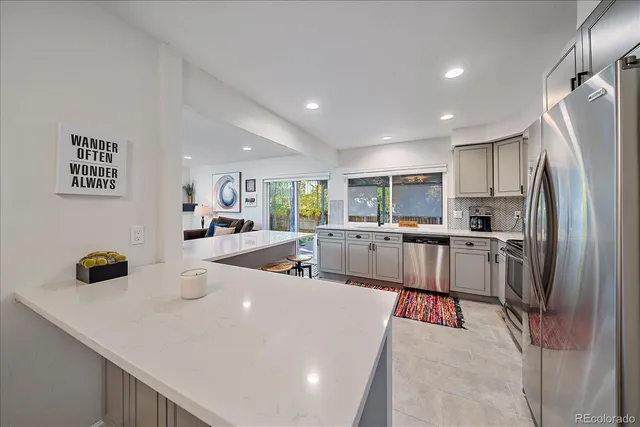 a kitchen with stainless steel appliances a dining table chairs refrigerator and microwave