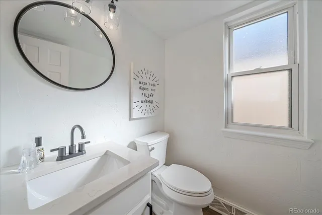 a bathroom with a toilet sink mirror and vanity